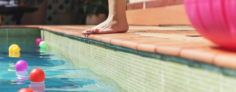 Man standing on the edge of a swimming pool in Little Elm, find homes for sale 