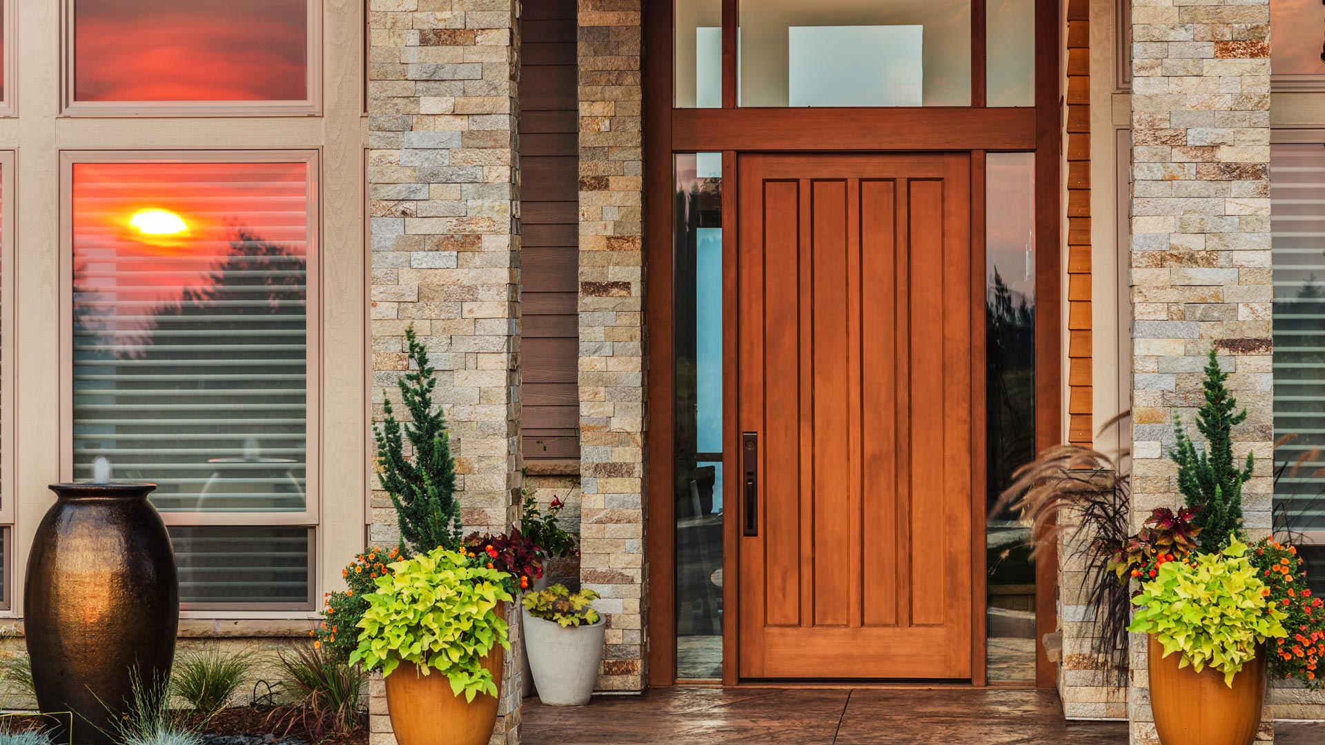 Front door with plants on the porch of upscale ranch home at sunset