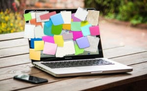 laptop screen being used as bulletin board with sticky notes