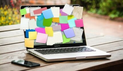 laptop screen being used as bulletin board with sticky notes