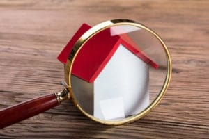 Magnifying glass in front of house representing home search or inspections