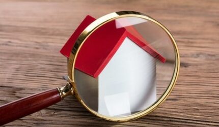Magnifying glass in front of house representing home search or inspections