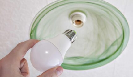 keep your home cooler with energy-saving LED light bulb and a persons hand.