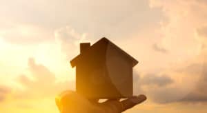 Symbolic house being held up to the sunset