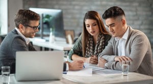 Mortgage lender reviewing documents with young couple