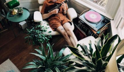 Relaxed man playing guitar and surrounded by house plants
