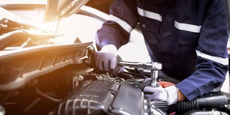 Auto mechanic under the hood of a car getting it ready for a road trip