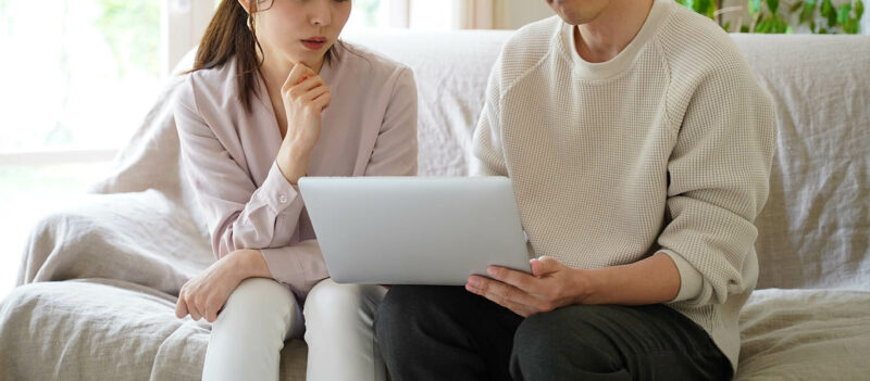 Couple on sofa looking at laptop for new home 
