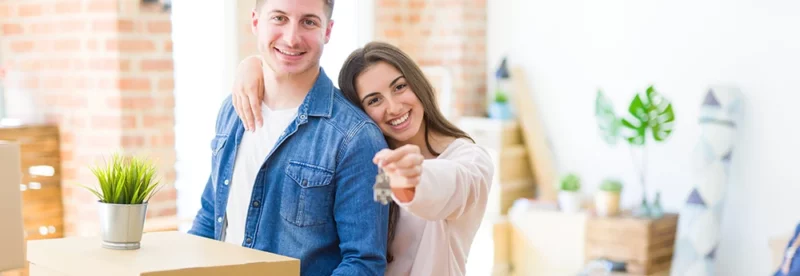 First-time homebuyers with moving boxes and keys to their new home