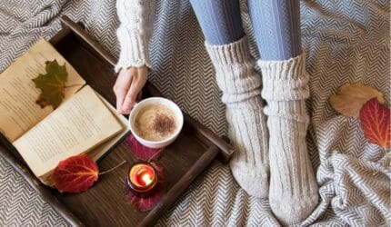 Lady wearing cozy winter clothes, hot coffee, book on a fall day